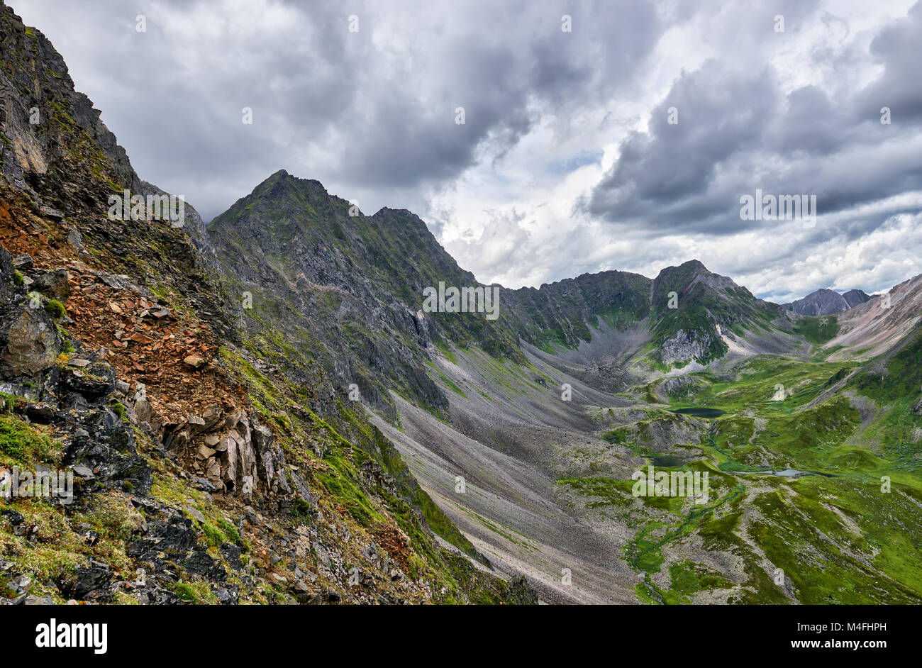 Mountain range and upper valley below. Gloomy cloudy sky. East Sayan. Russia Stock Photo