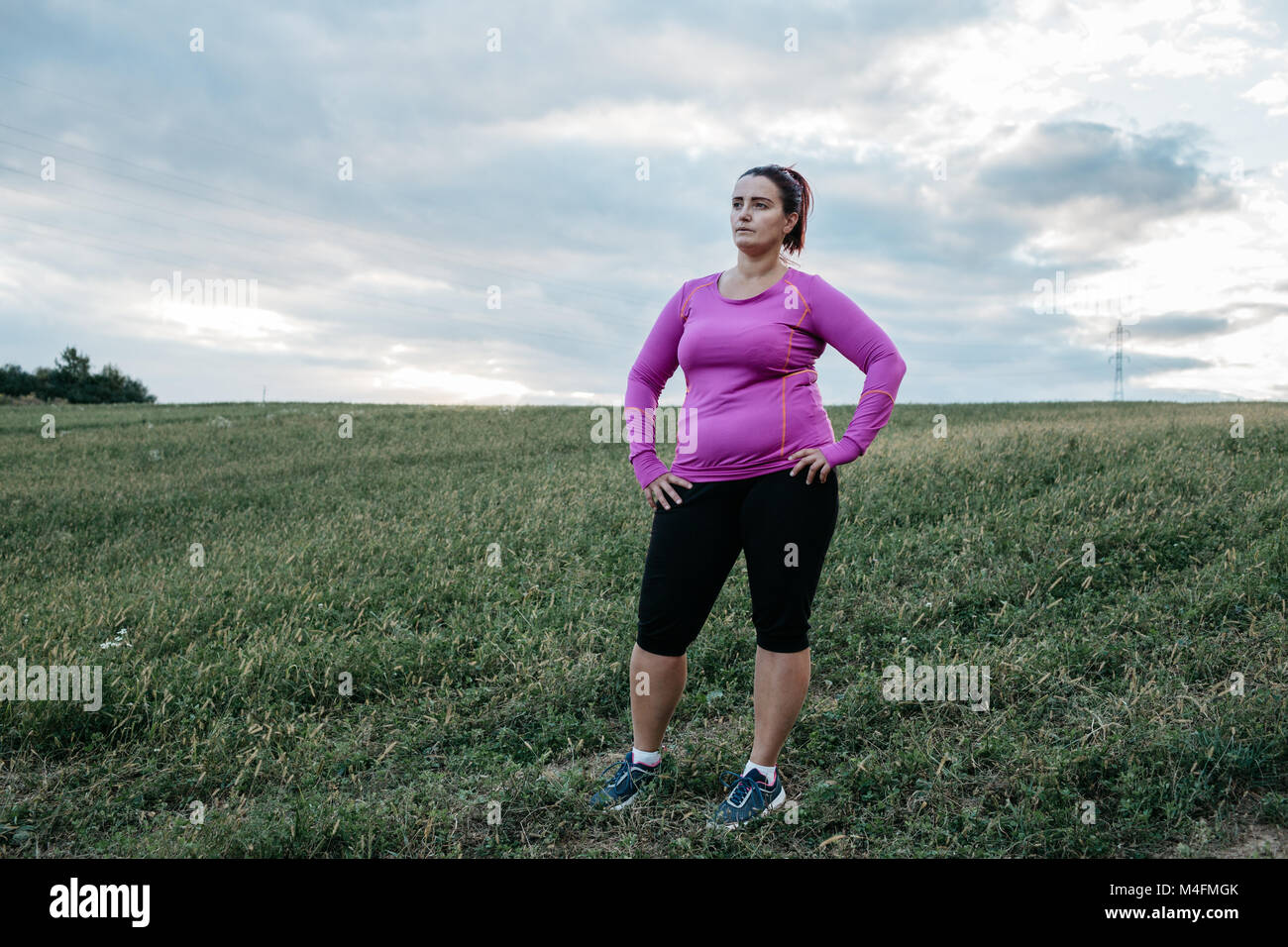 Portrait of a plus size female runner looking into distance and resting. Stock Photo