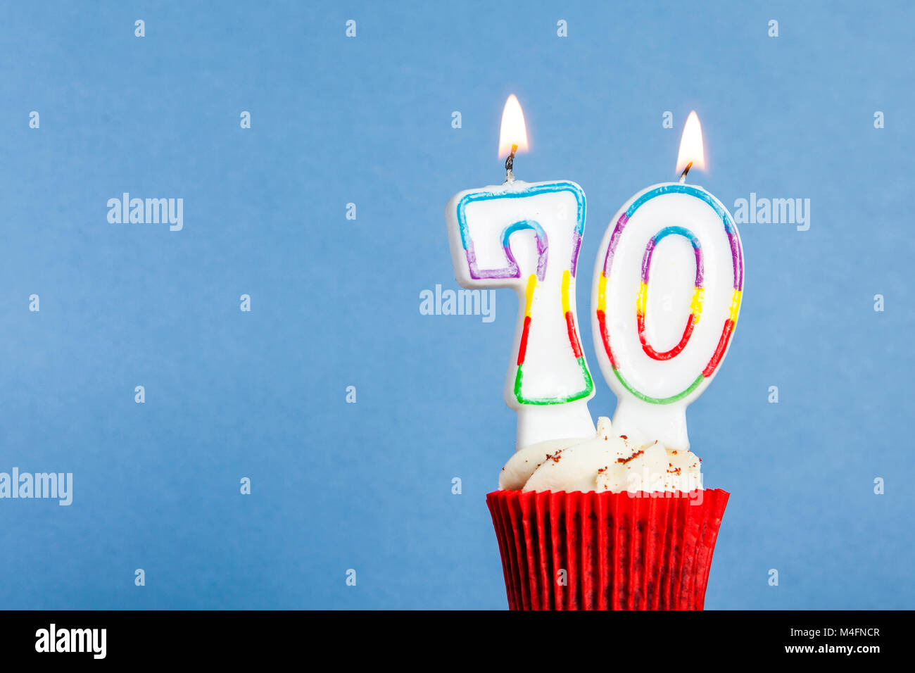 Number 70 birthday candle in a cupcake against a blue background Stock Photo