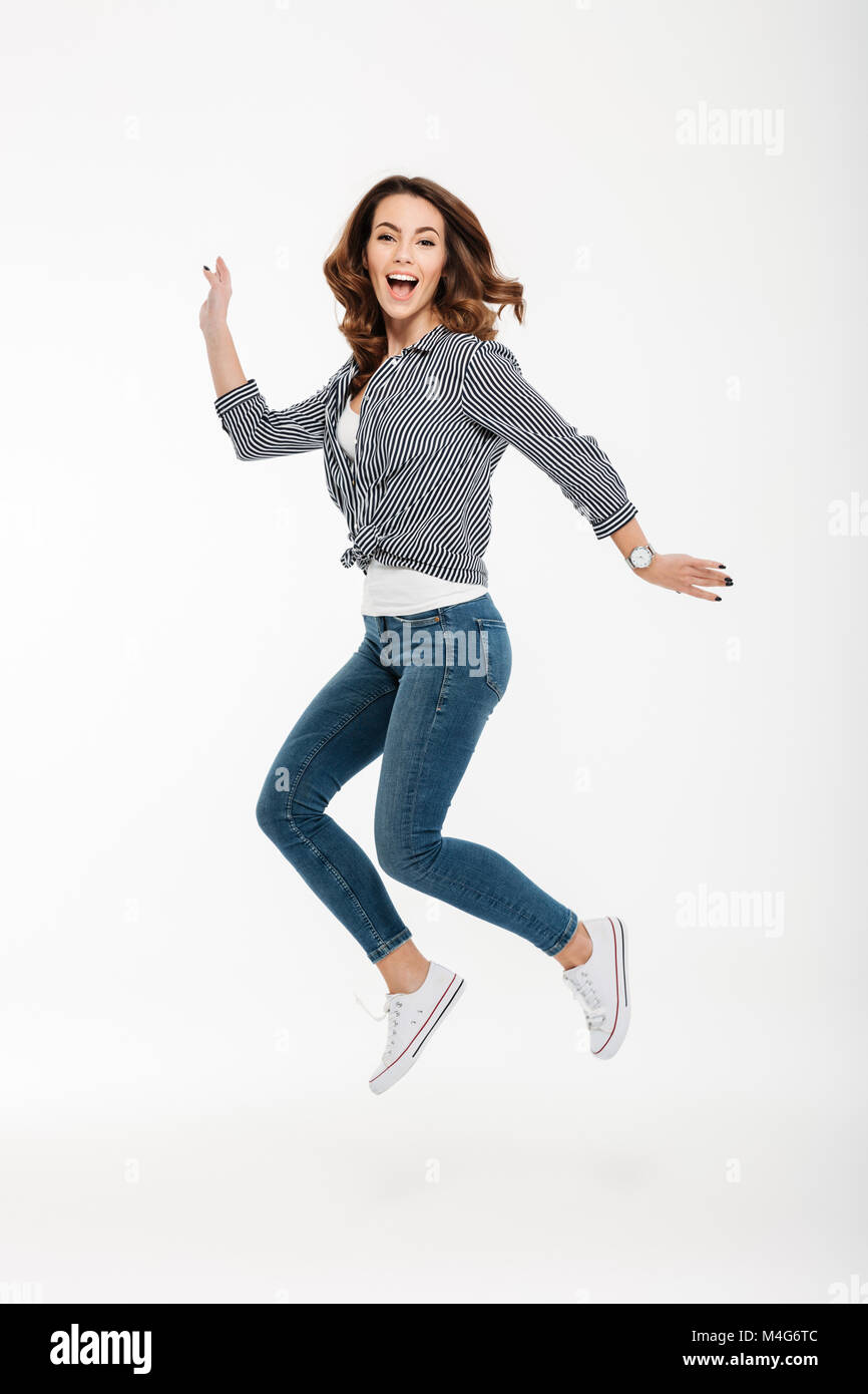 Full length portrait of a happy casual girl jumping isolated over white ...