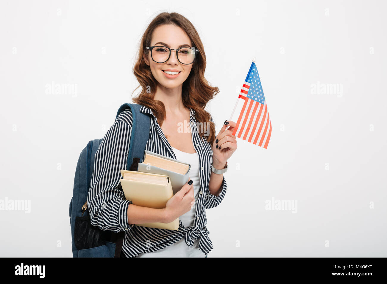 Portrait of a smiling casual girl student with backpack holding books ...