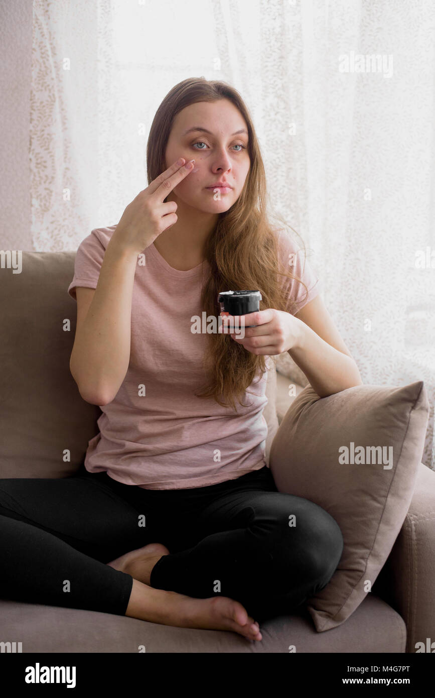 Portrait of attractive young woman sitting on couch at home Stock Photo ...