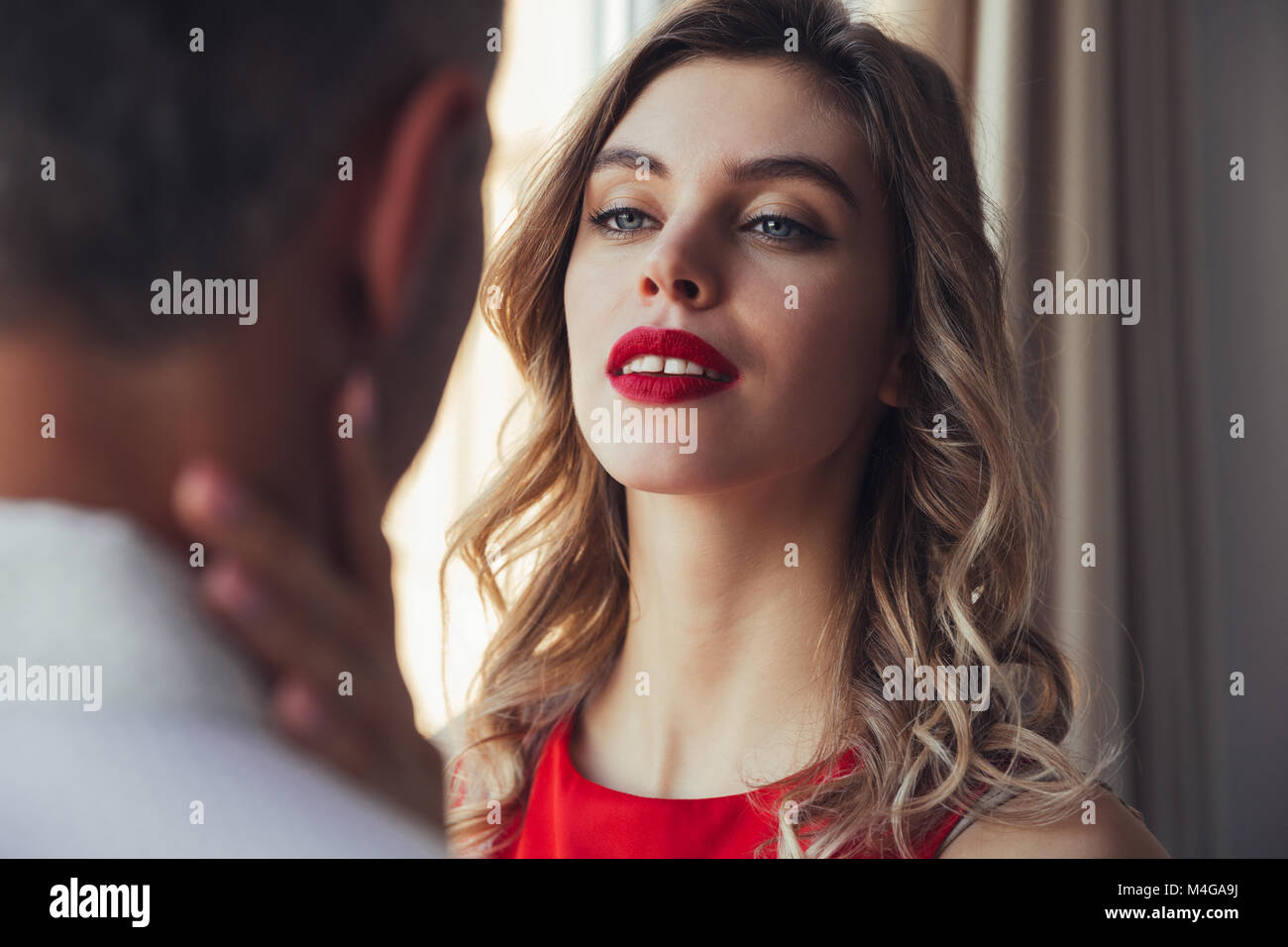 Serious Beautiful Woman Flirting And Hug Her Man In White Shirt While Posing Near Window Stock