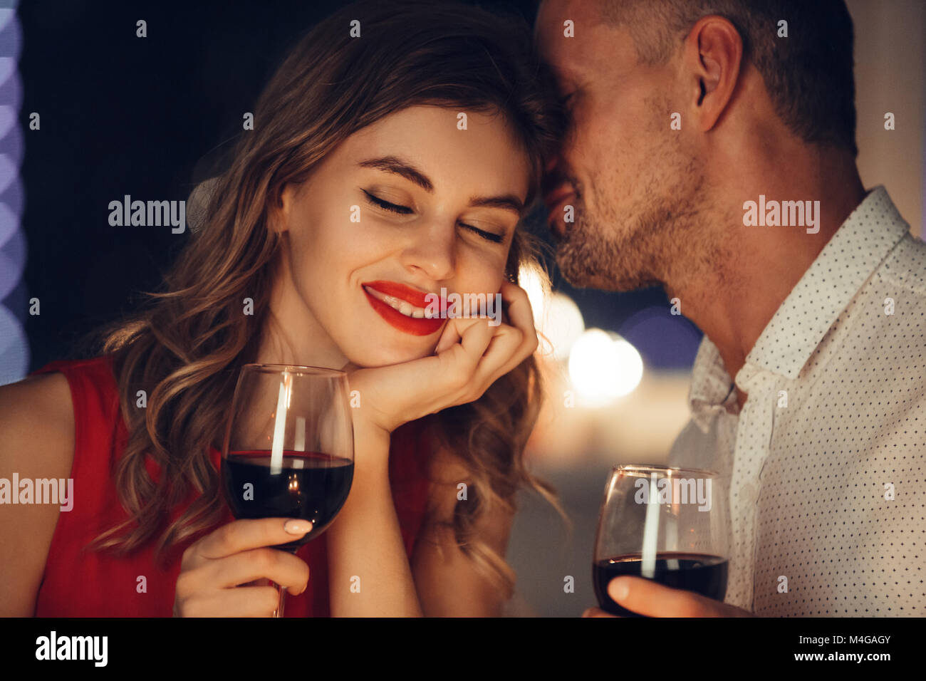 Young handsome man whisper to his gorgeous woman while have romantic dinner and drinking wine on valentines day Stock Photo