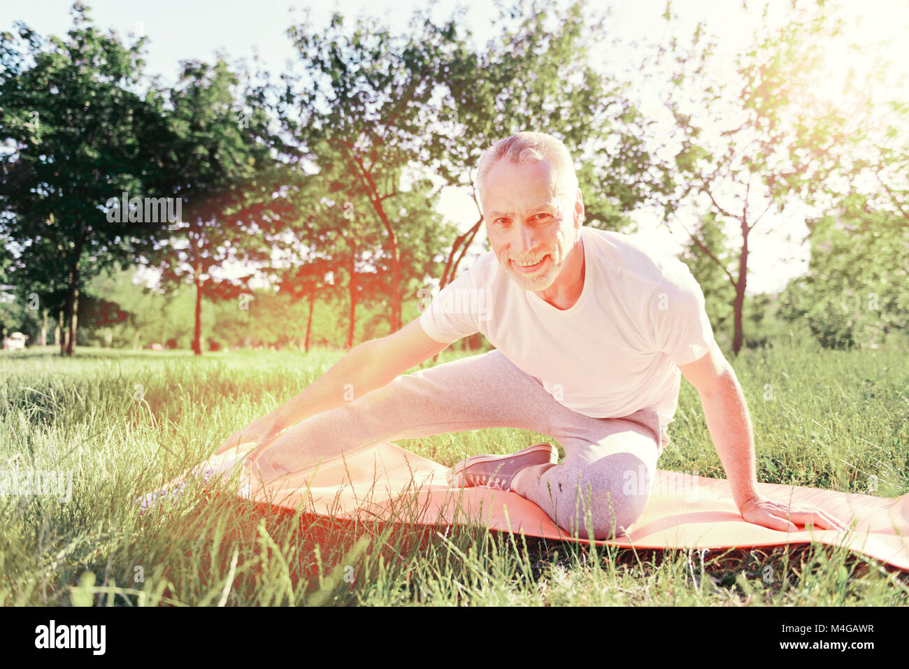 Enthusiastic man doing exercises on the ground pad Stock Photo