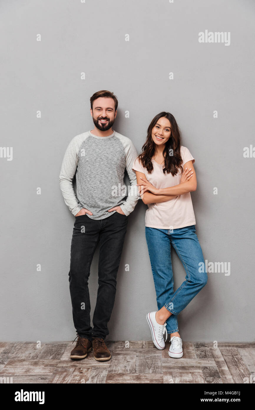 Full length portrait of a smiling young couple standing together and ...