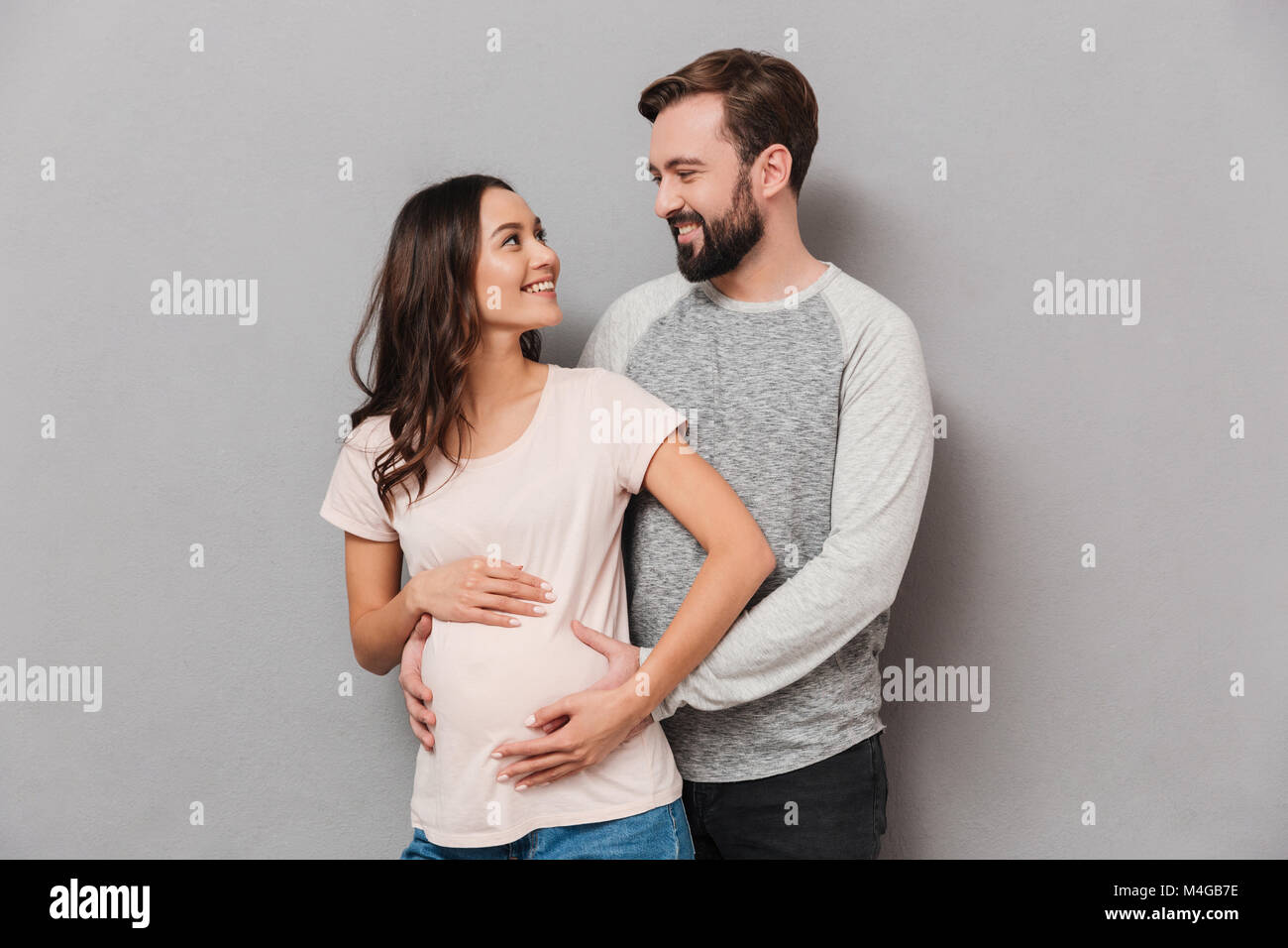 Portrait of a beautiful young man hugging his pregnant wife while ...