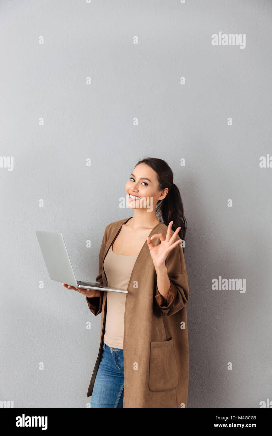 Portrait of a confident young asian woman holding laptop computer while ...