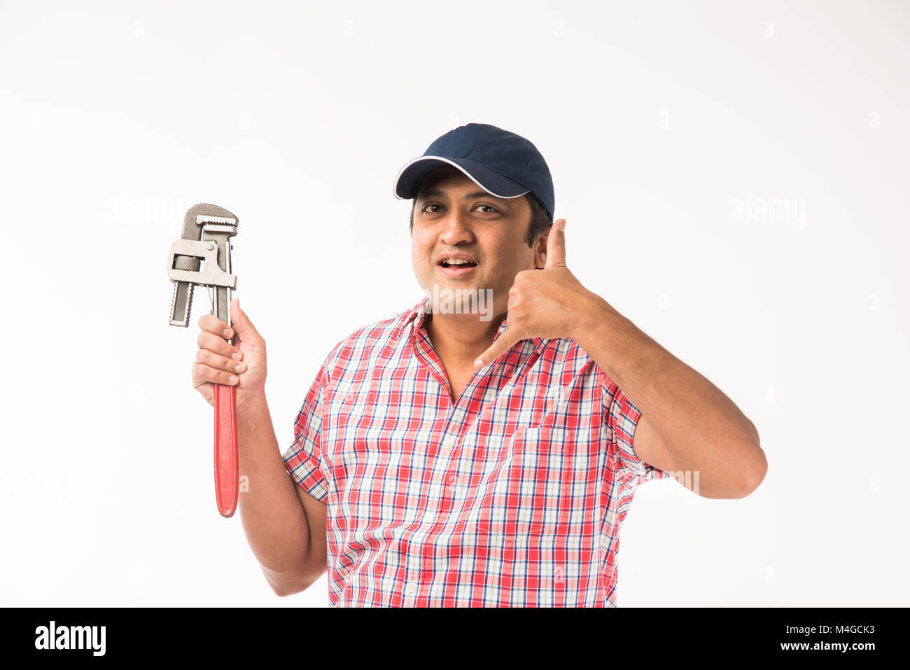 Indian plumber posing with Pipe wrench or plumbing spanner, standing
