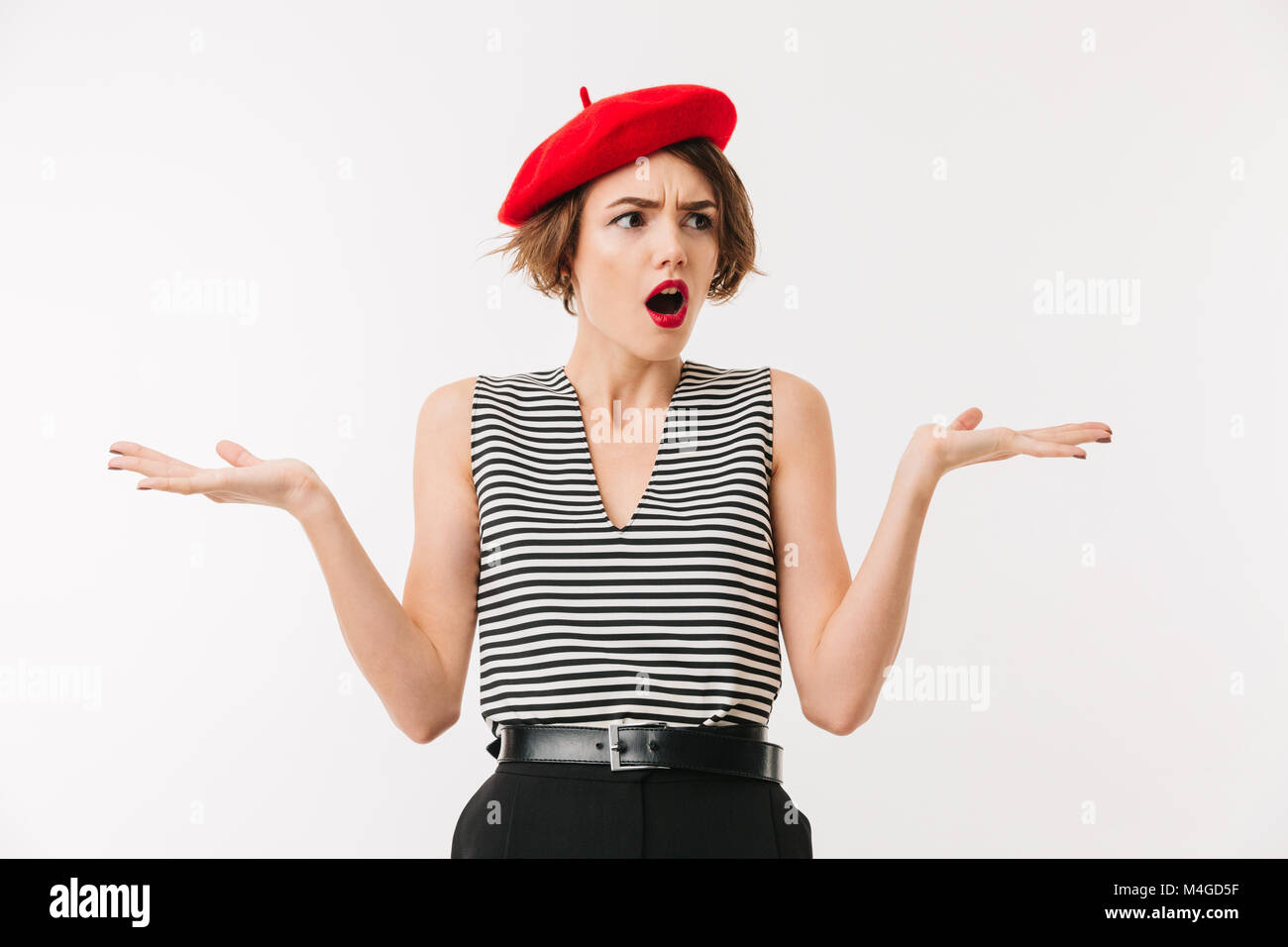 Portrait of a confused woman wearing red beret shrugging shoulders isolated over white background Stock Photo