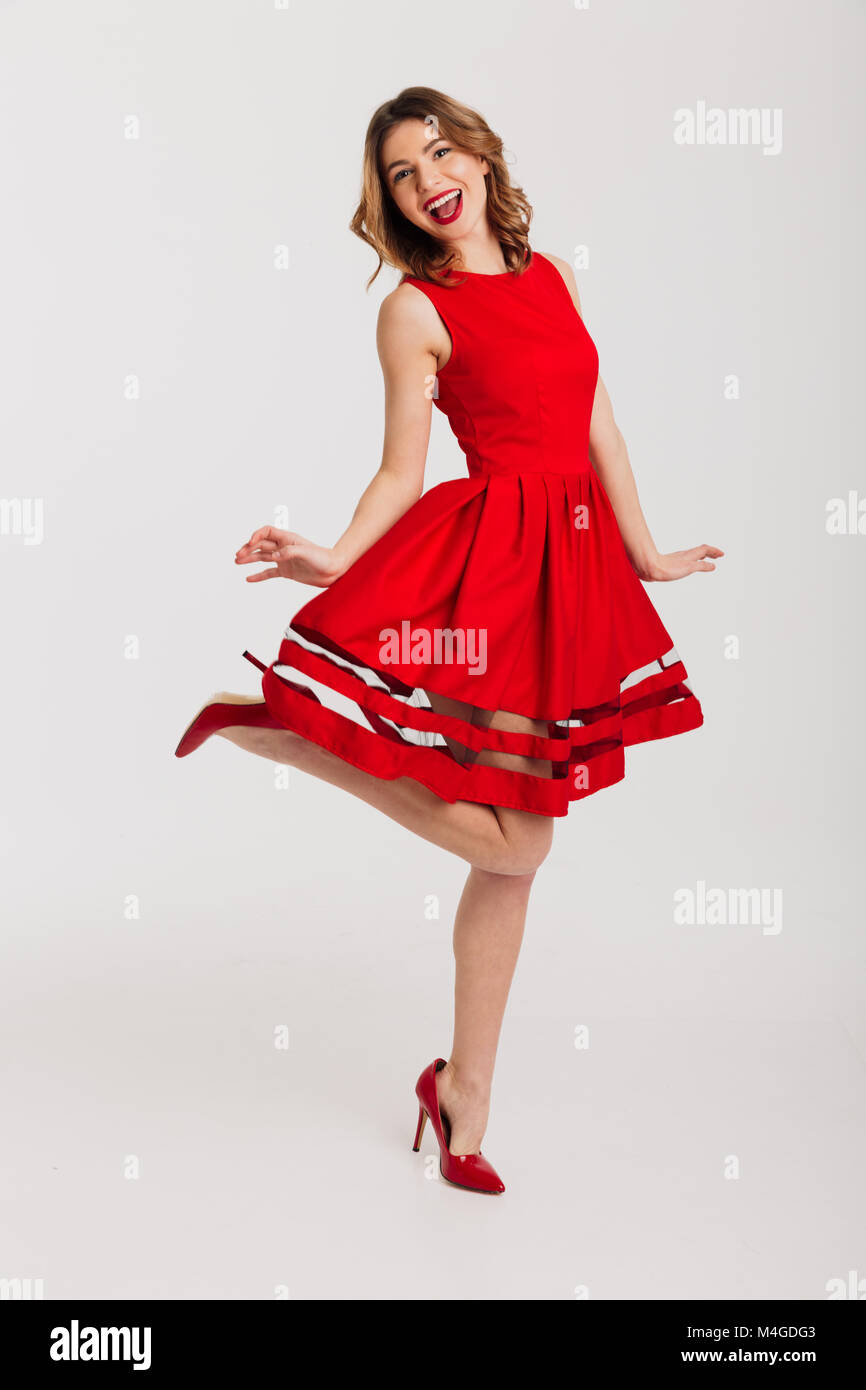 Full length portrait of a happy young girl dressed in red dress posing ...