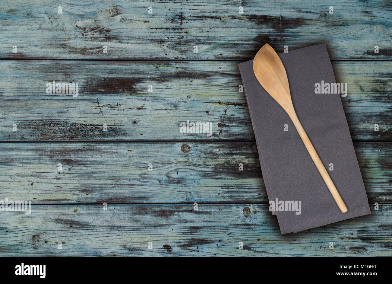 Wooden spoon and kitchen towel on turquoise vintage wood. Stock Photo