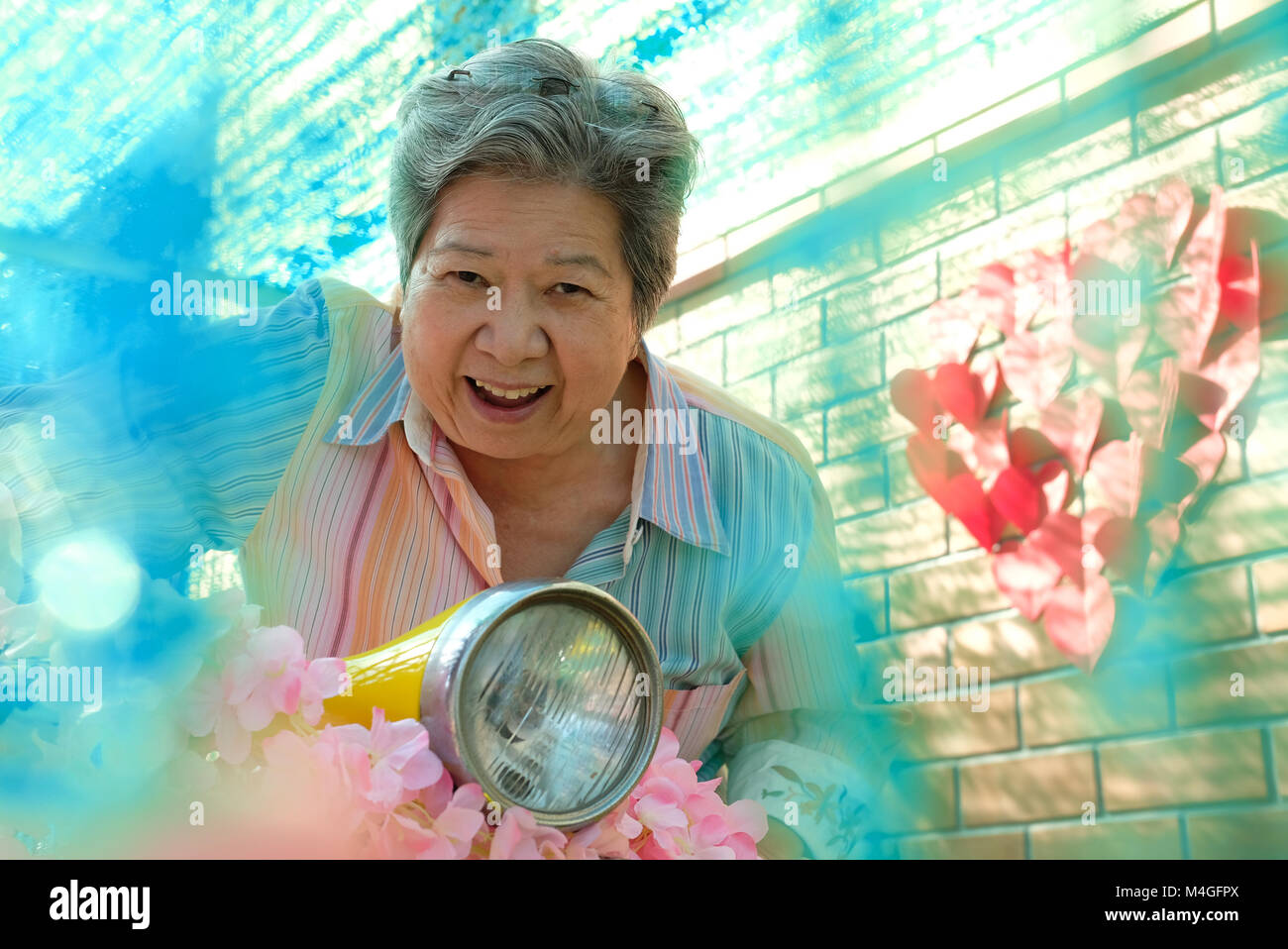 asian elder woman riding motorcycle. happy elderly female on yellow motorbike. fun mature lifestyle concept Stock Photo
