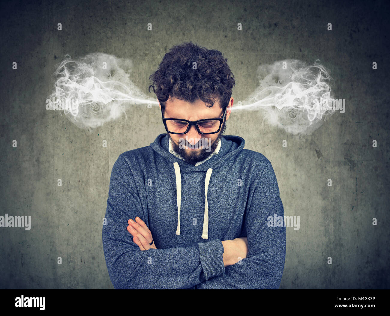 Angry young man, blowing steam coming out of ears, about to have nervous breakdown isolated on gray background. Negative human emotions face expressio Stock Photo