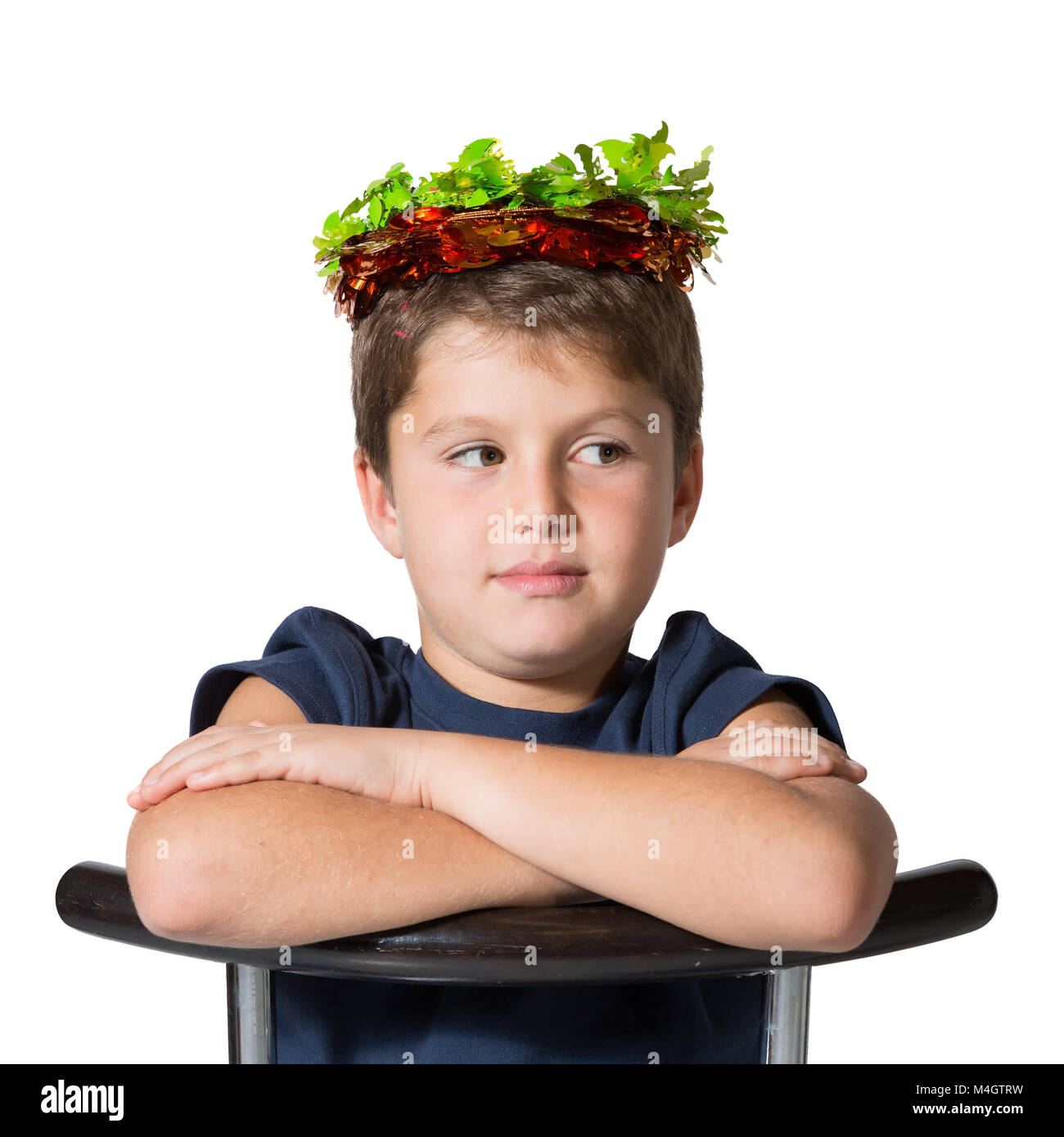 Boy sits astride a chair in carnival wearing a crown Stock Photo