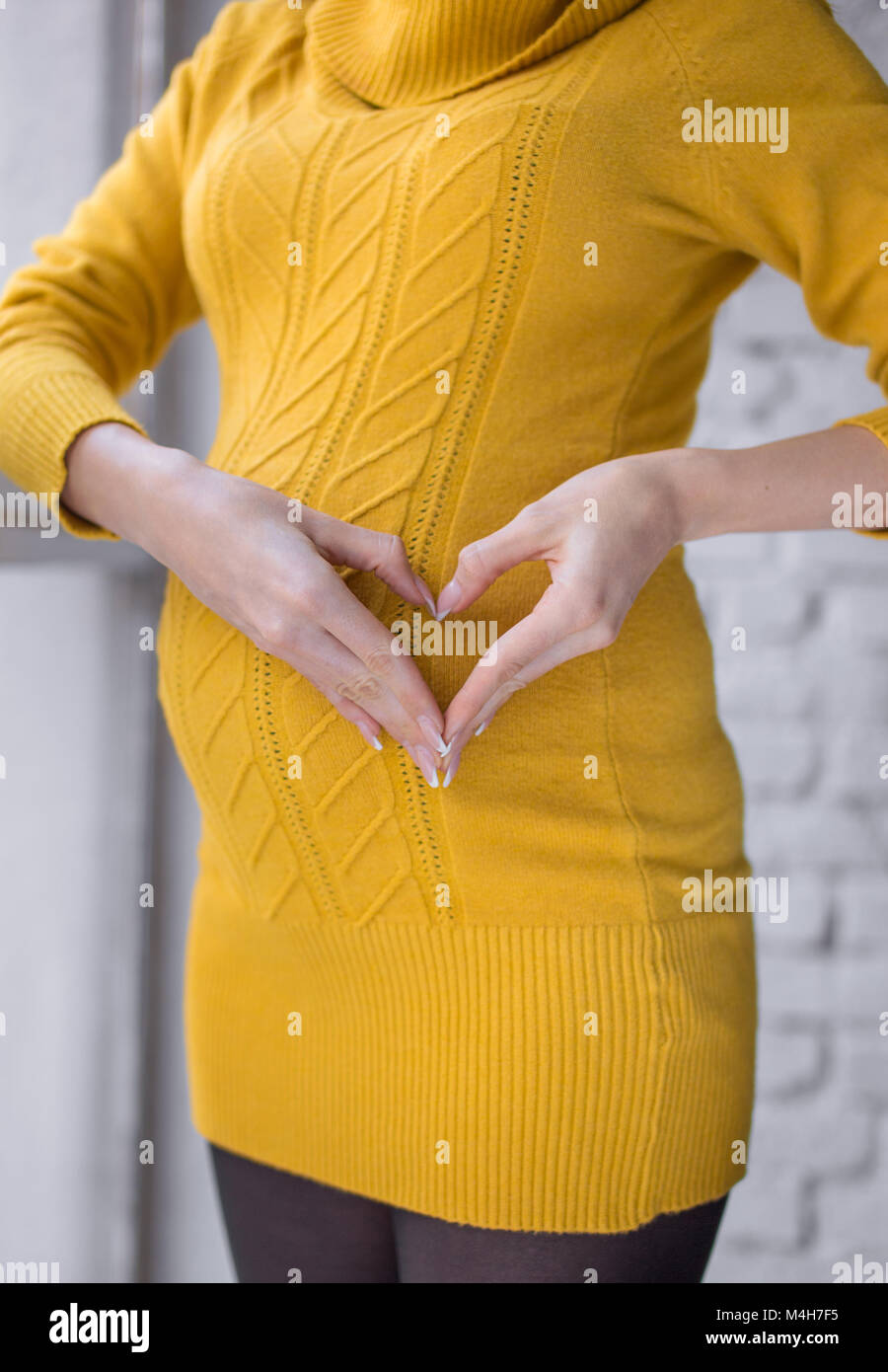 Pregnancy, motherhood, expectation concept - happy pregnant woman with big belly showing love sign Stock Photo