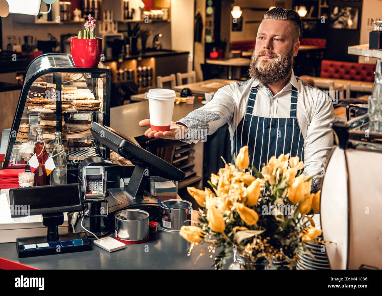 https://c8.alamy.com/comp/M4H886/positive-bearded-barista-male-selling-coffee-to-a-consumer-in-a-coffee-M4H886.jpg