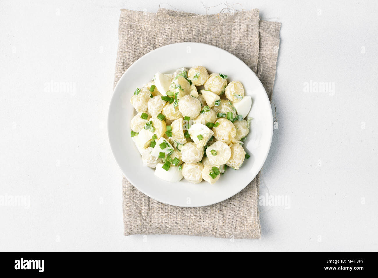 German potato salad with eggs and green onion, dressing with yoghurt and mayonnaise on white