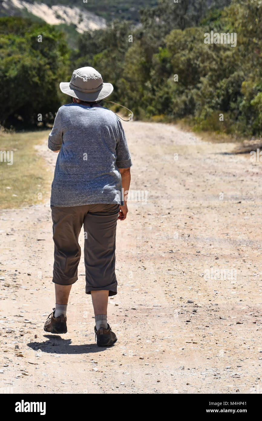 A woman in hiking outfit  on a gravel road in Goukamma Knysna on the Garden Route in South Africa Stock Photo