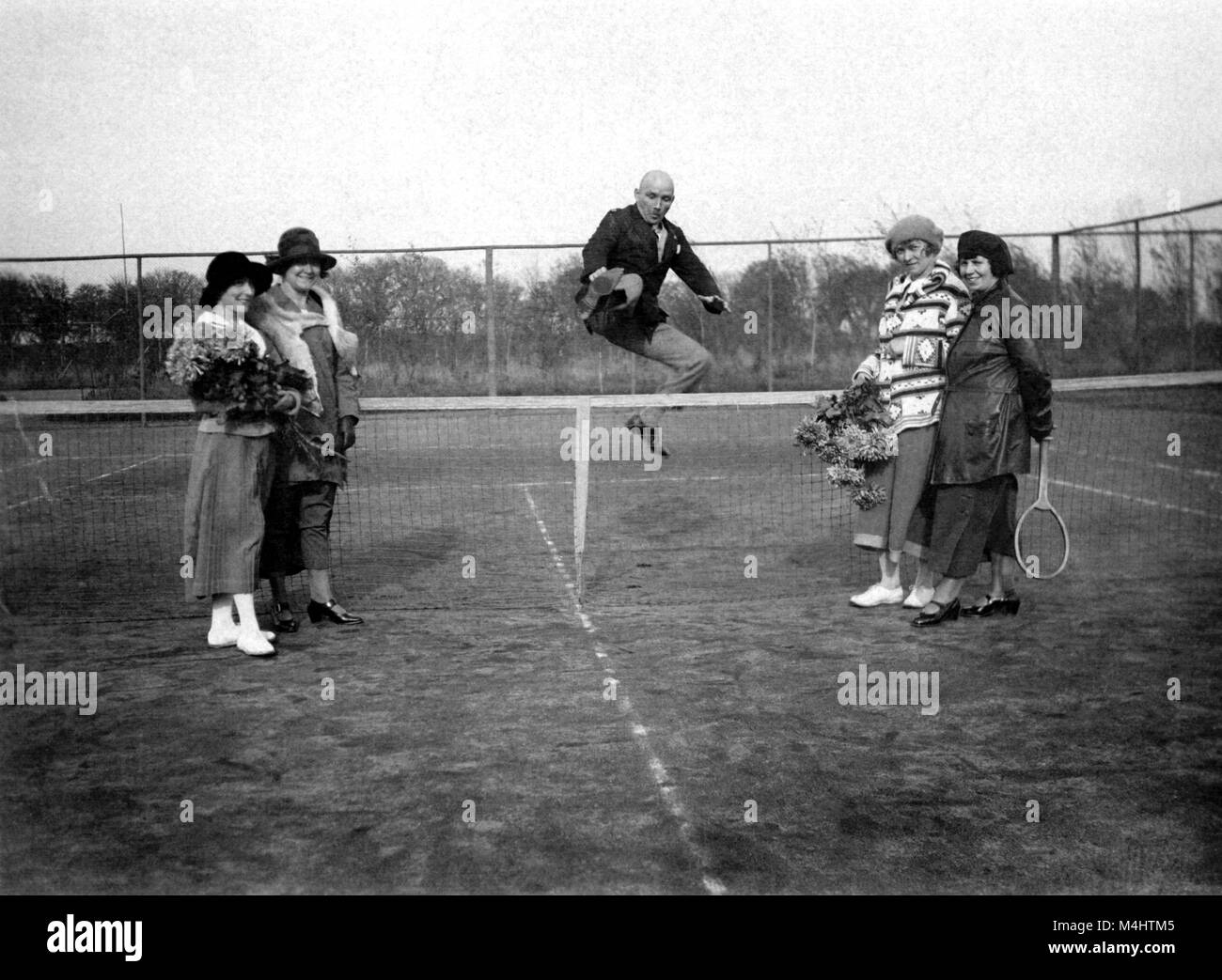 Bragger on the tennis court, man jumps over the tennis net to impress four women, ca. 1928, 1920s, exact place unknown, Germany Stock Photo