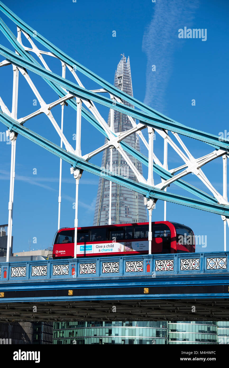 Red London bus crossing Tower Bridge with the Shard in the background, London, England, UK Stock Photo