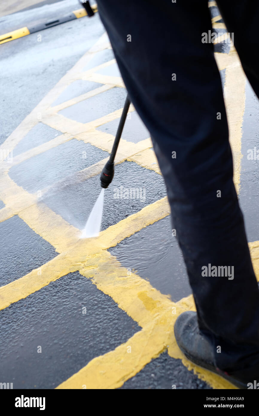 February 2018 - man jet washing the yellow lines of a disabled parking bay outside a McDonald's restaurant in Portishead, near Bristol. Stock Photo