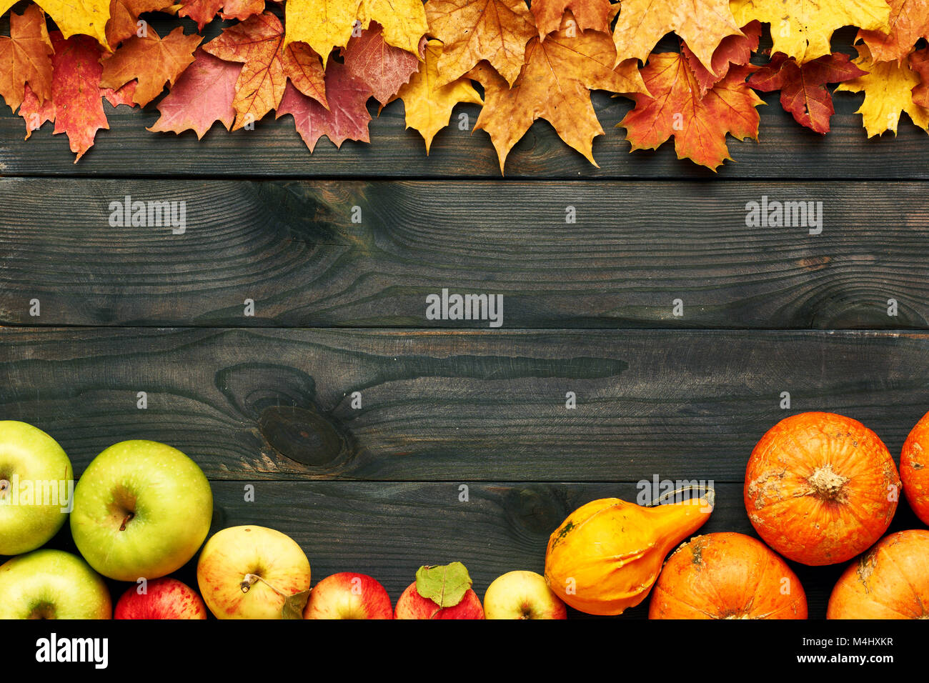 Autumn leaves, apples and pumpkins over wooden background Stock Photo ...