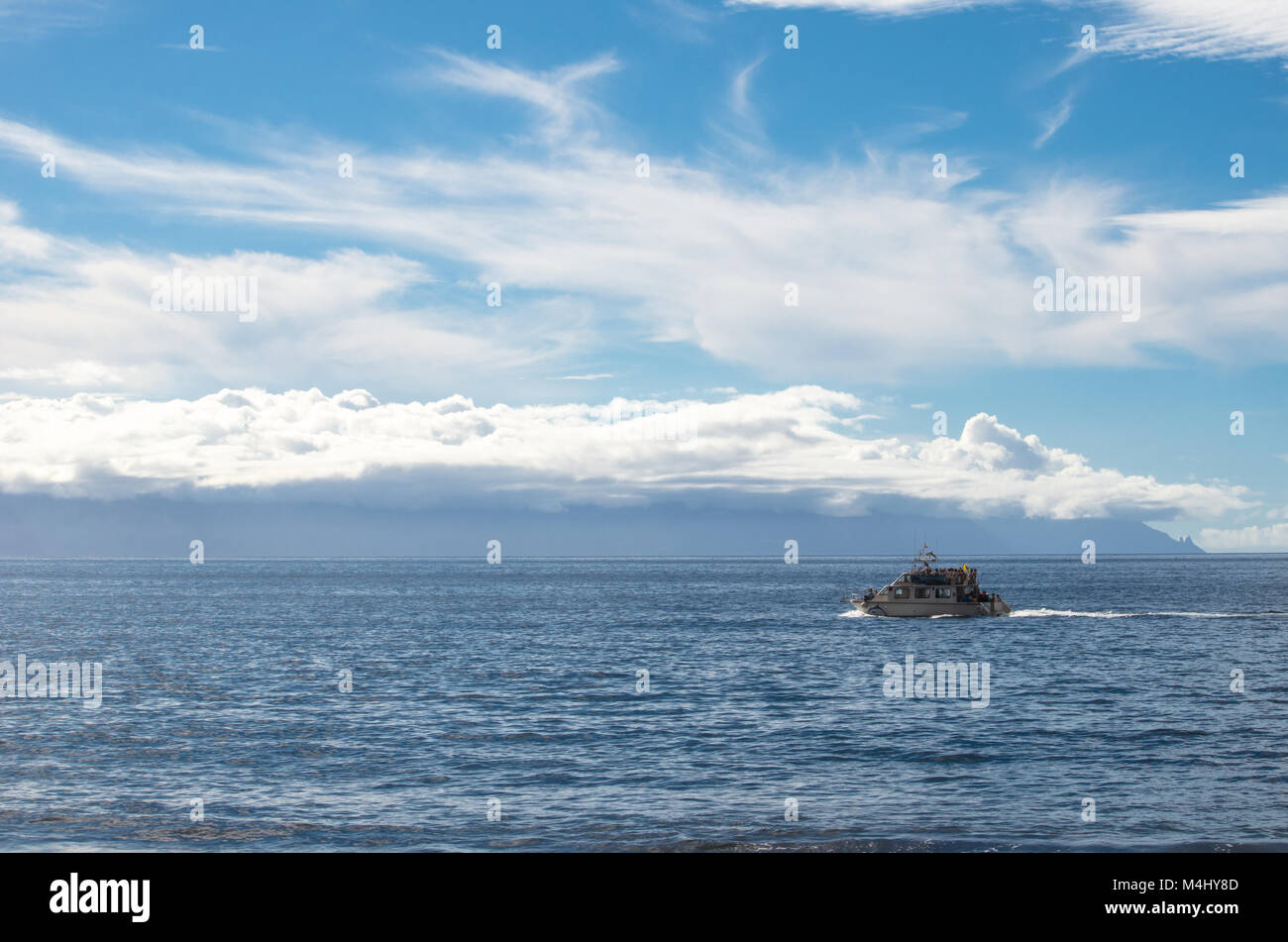 A boat with tourists on the Atlantic Ocean with the island of La Gomera in the background in the Canary Islands. View from Tenerife Stock Photo