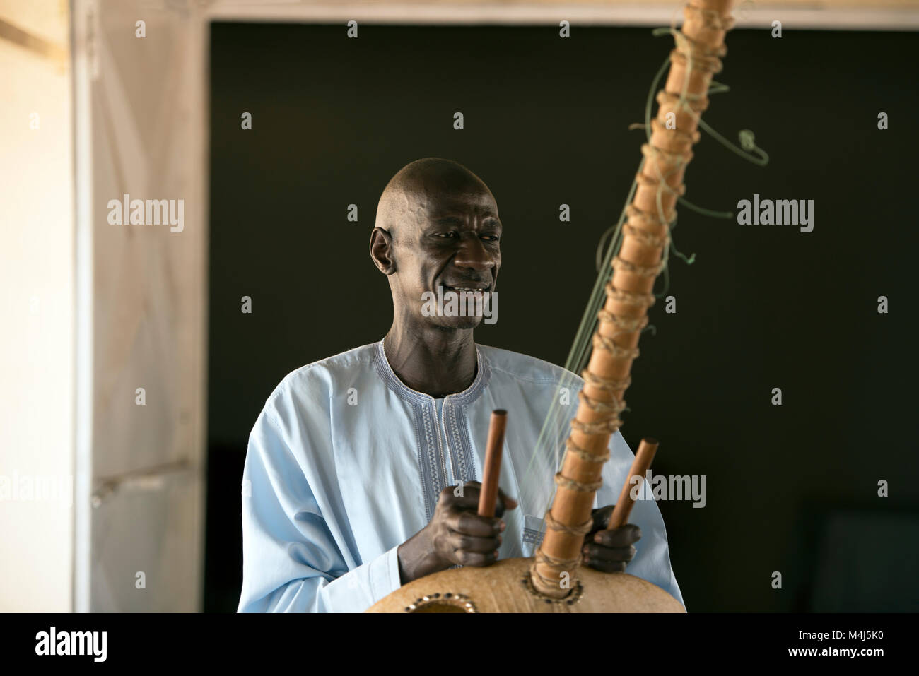 An ethnic Mandinka tribesman plays the Kora, a traditional musical instrument, in Jufureh, The Gambia, West Africa. Stock Photo