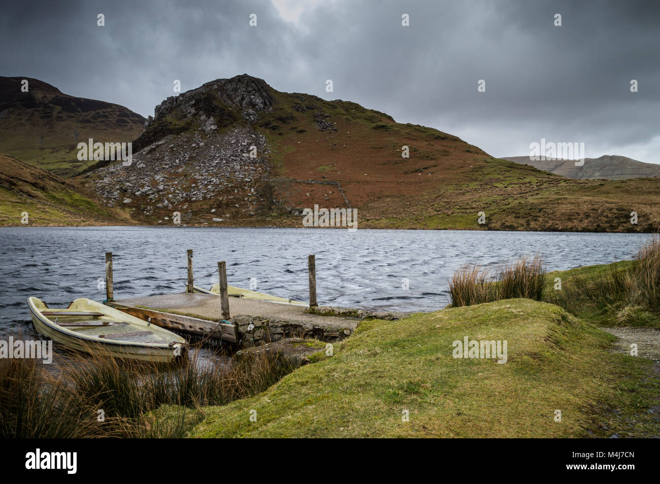 Two dilapidated boats moored at the jetty on Llyn Y Dywarchen in the Snowdonia National Park, Wales. Stock Photo