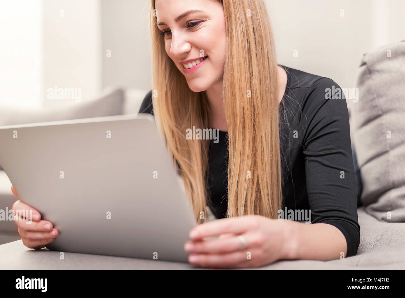 Attractive woman using a laptop while lying on the couch at home Stock ...