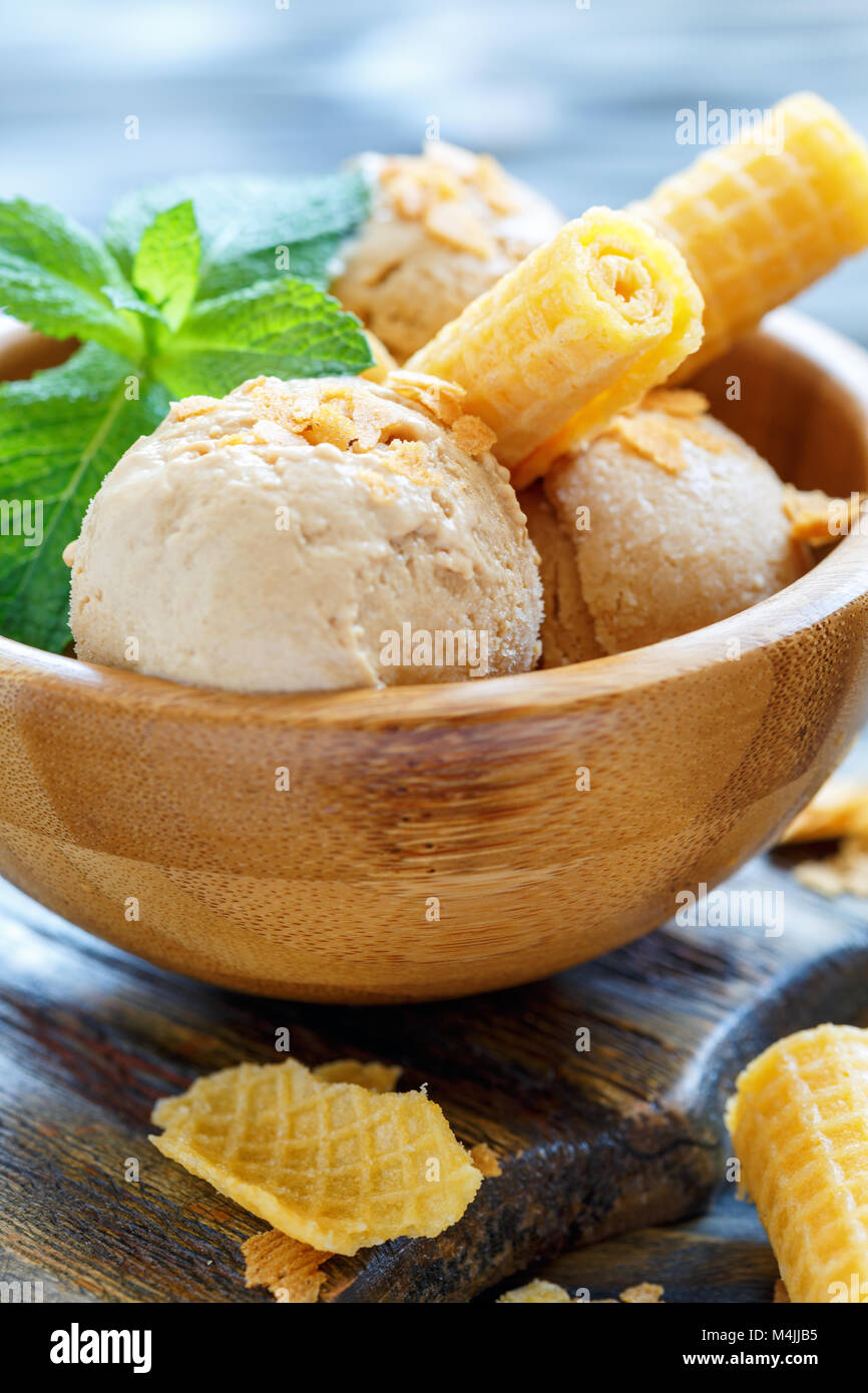 Caramel ice cream and wafer rolls in wooden bowl. Stock Photo