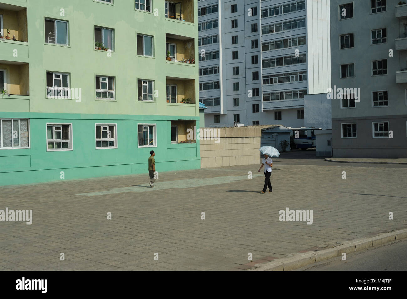 08.08.2012, Pyongyang, North Korea, Asia - Pedestrians walk by residential buildings in central Pyongyang. Stock Photo