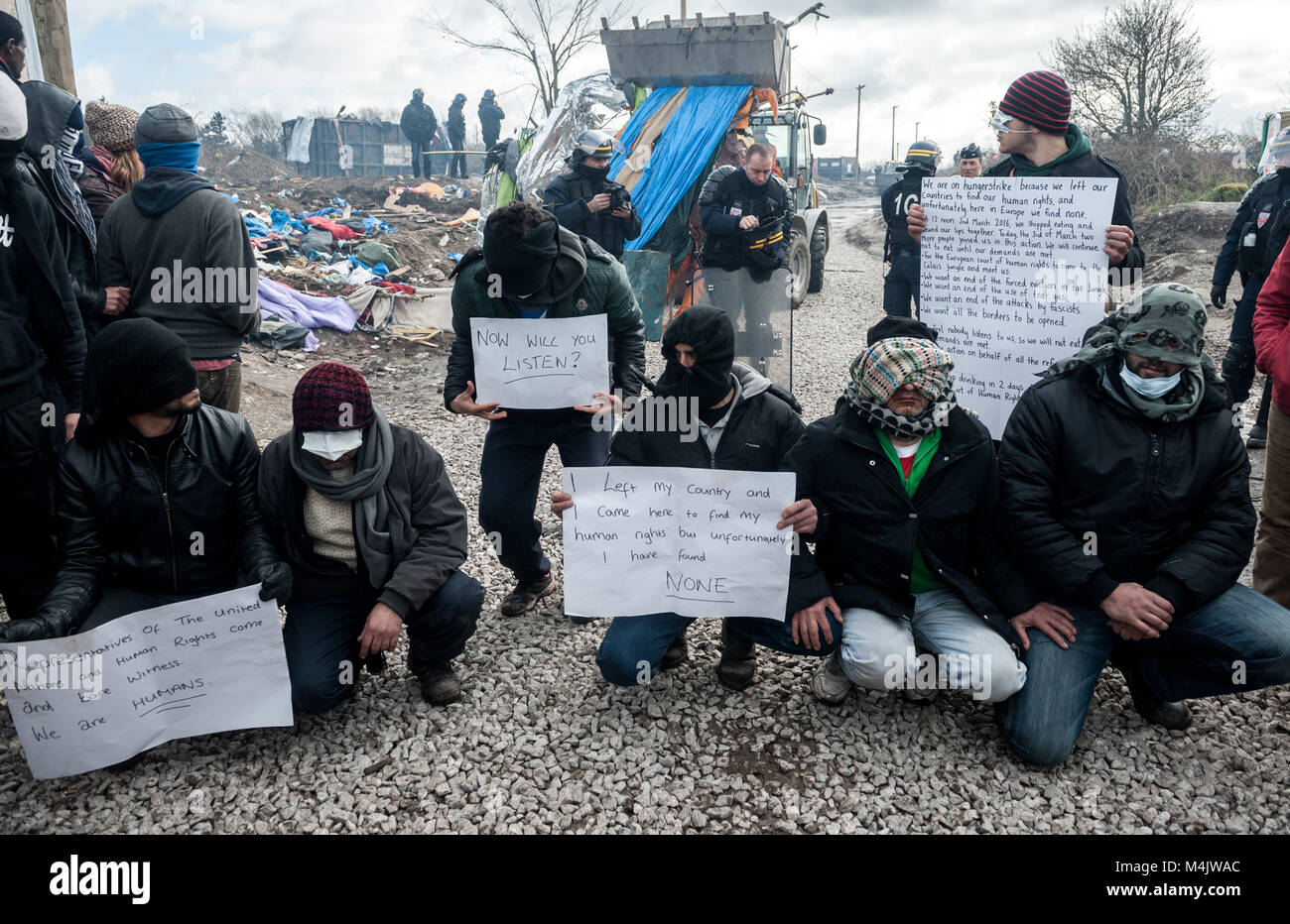 Calais Jungle, Northern France. 02 March, 2016. A group of Iranian asylum seekers stitch up their mouths to signify that their voices are not being heard by the French authorities demolishing the Calais Jungle refugee camp near Calais in Northern France. Stock Photo
