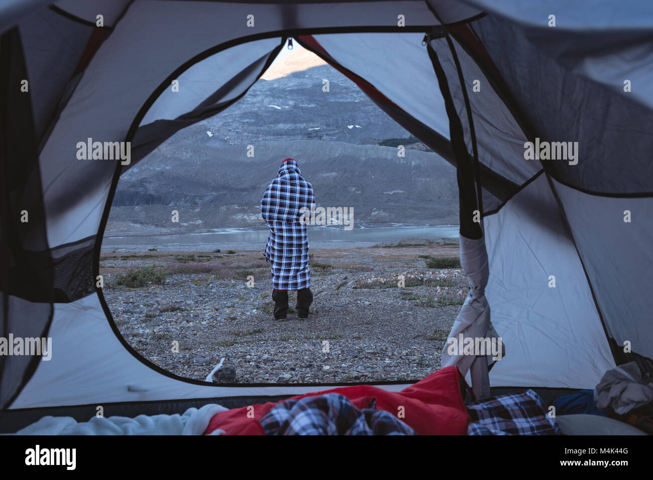 Man wrapped up in blanket near tent Stock Photo Alamy