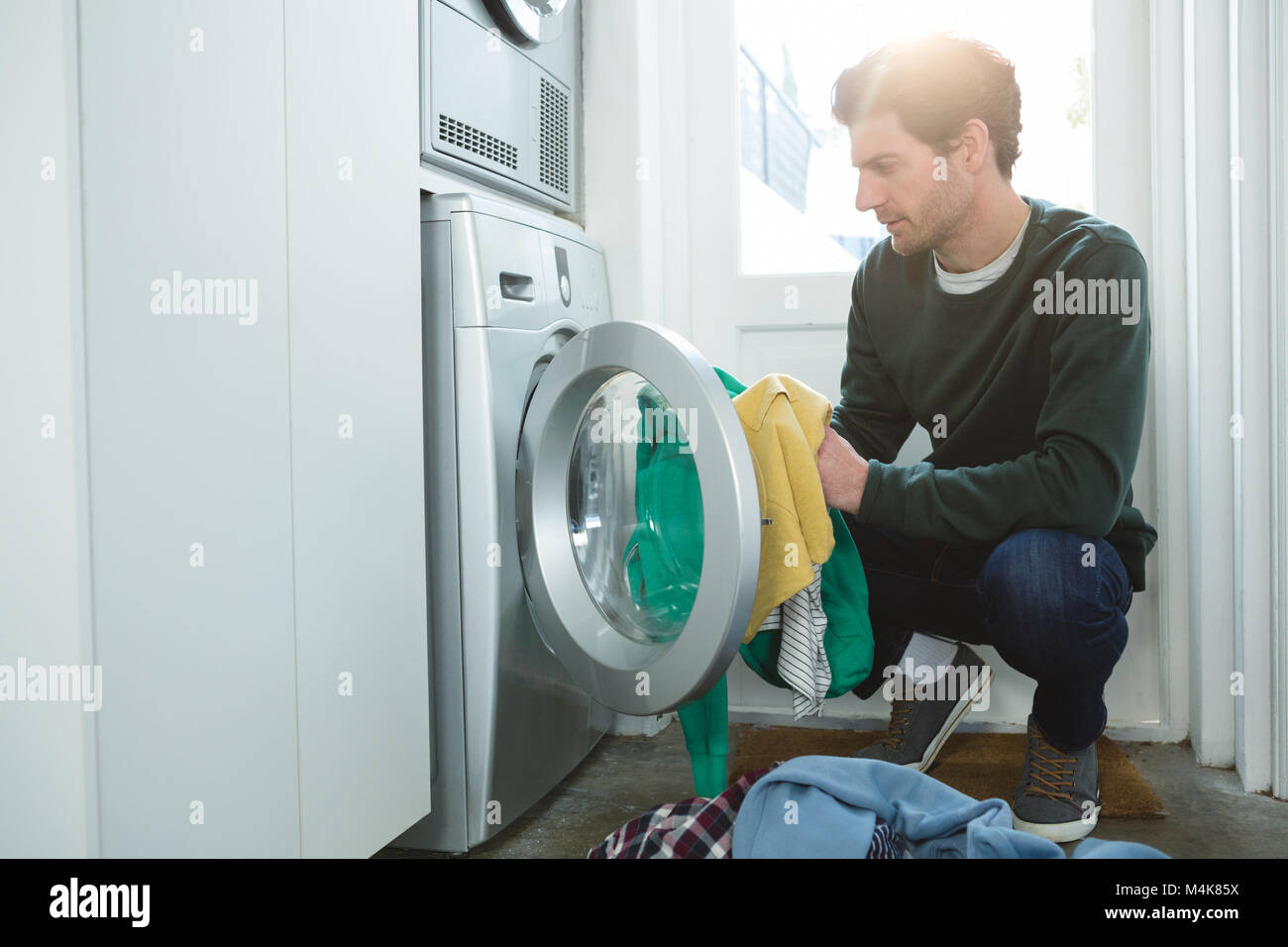 Man putting clothes in washing machine Stock Photo