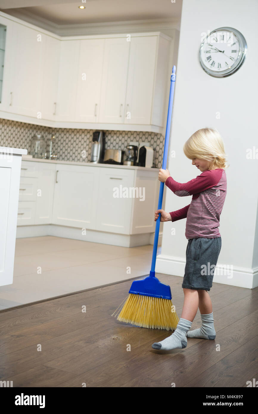 Boy cleaning floor with broom in kitchen Stock Photo Alamy