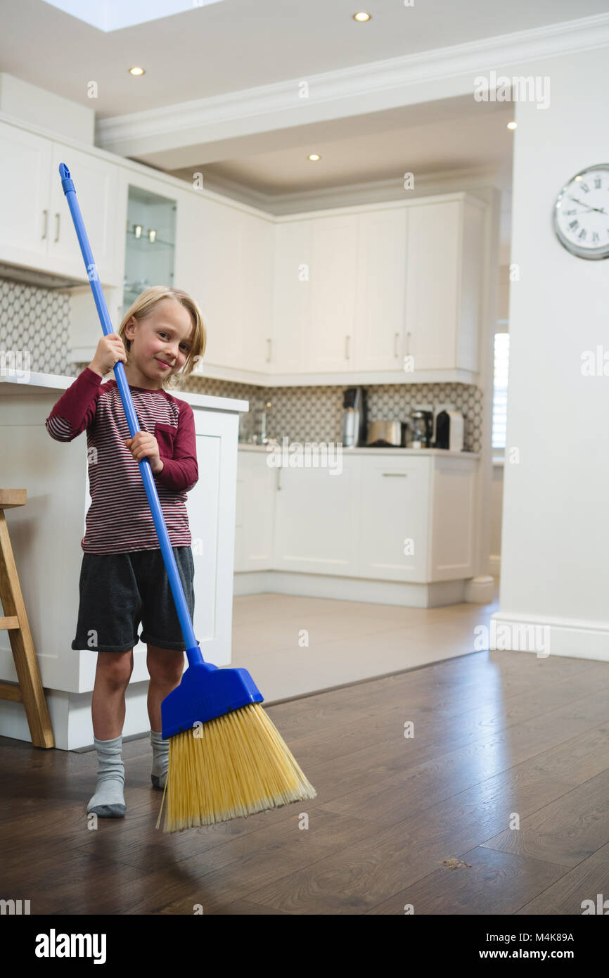 Boy cleaning floor with broom in kitchen Stock Photo Alamy