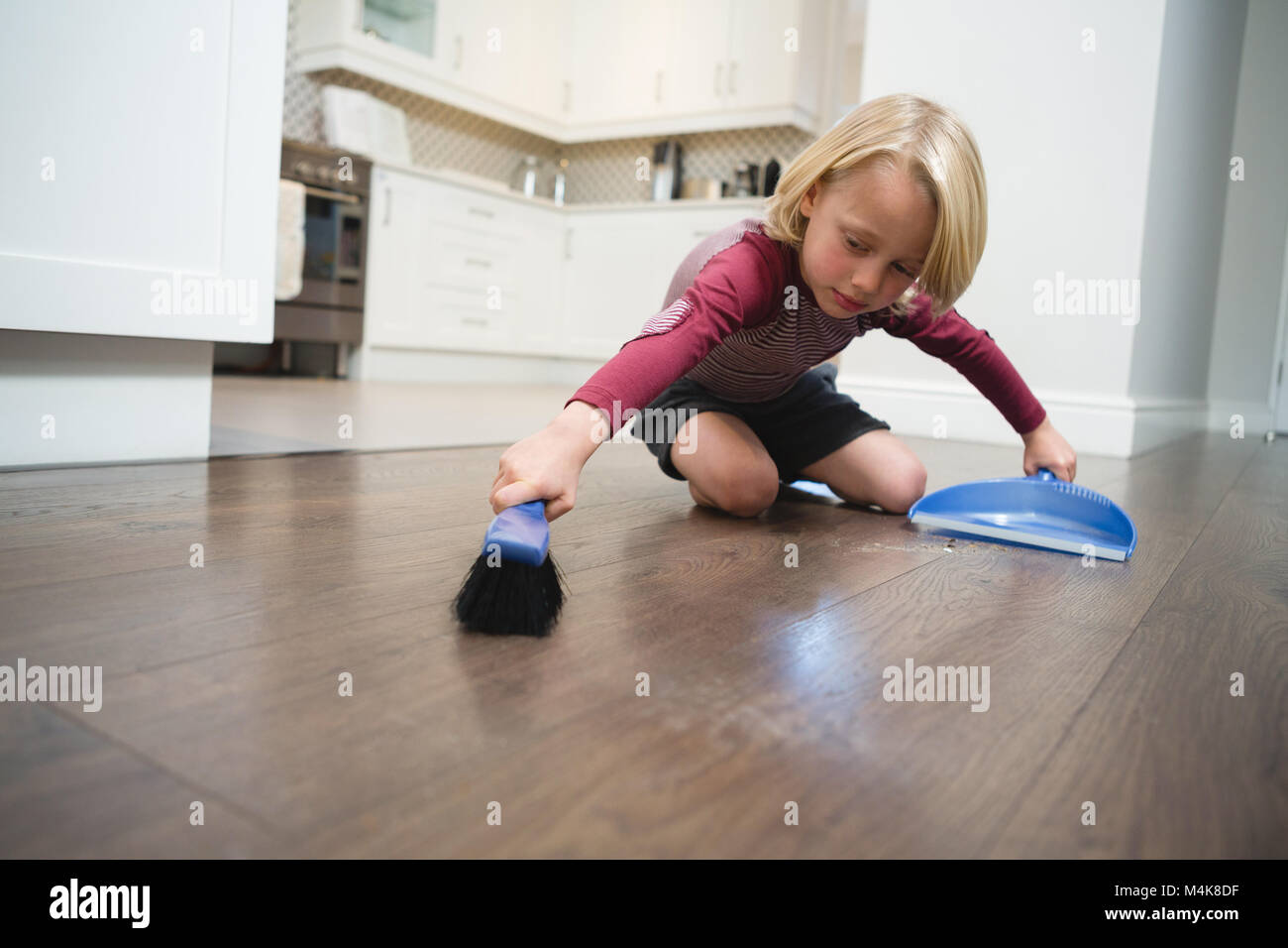 Boy sweeping dust with brush and dust pan Stock Photo