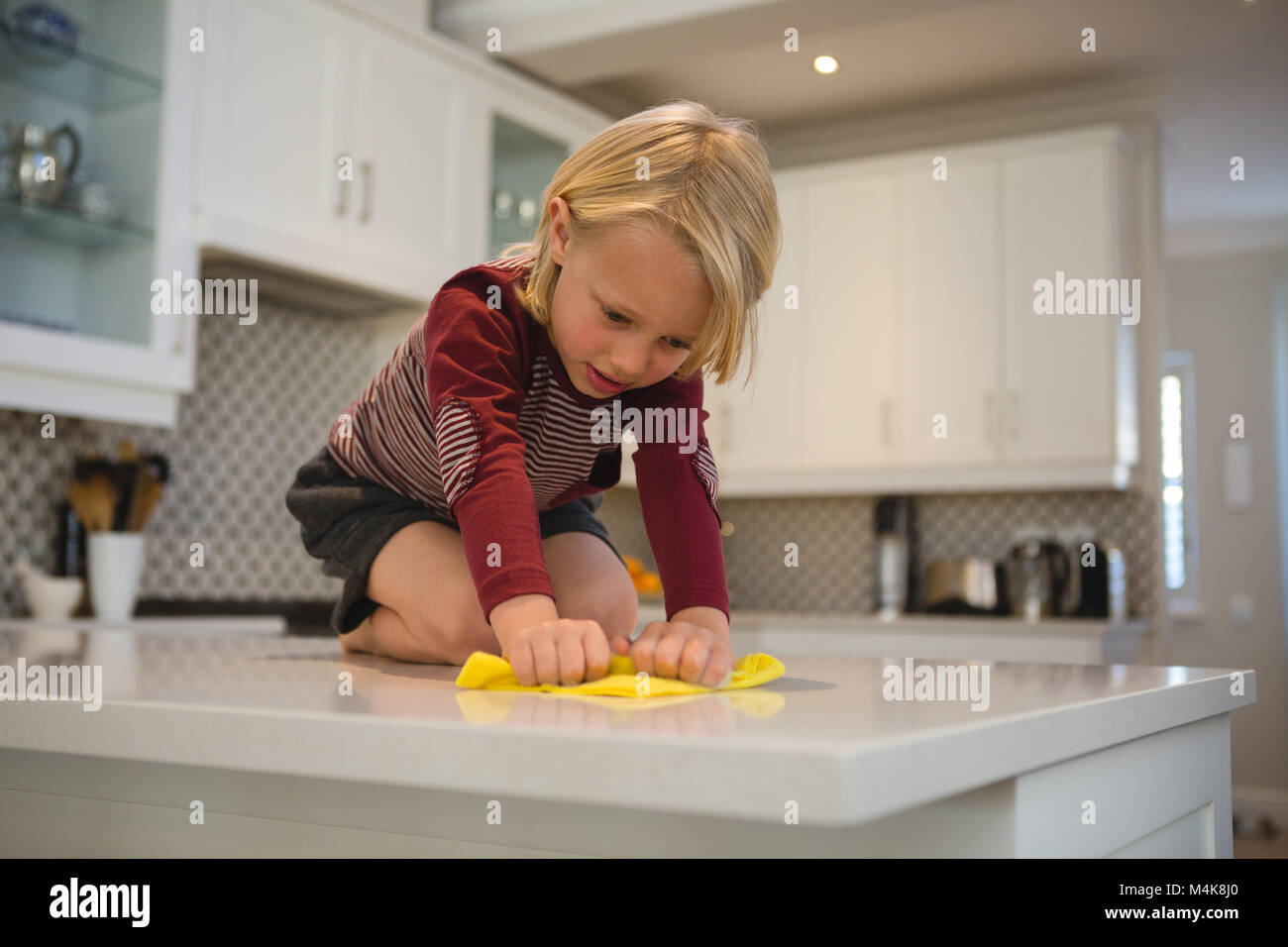 Boy cleaning kitchen worktop with rag Stock Photo