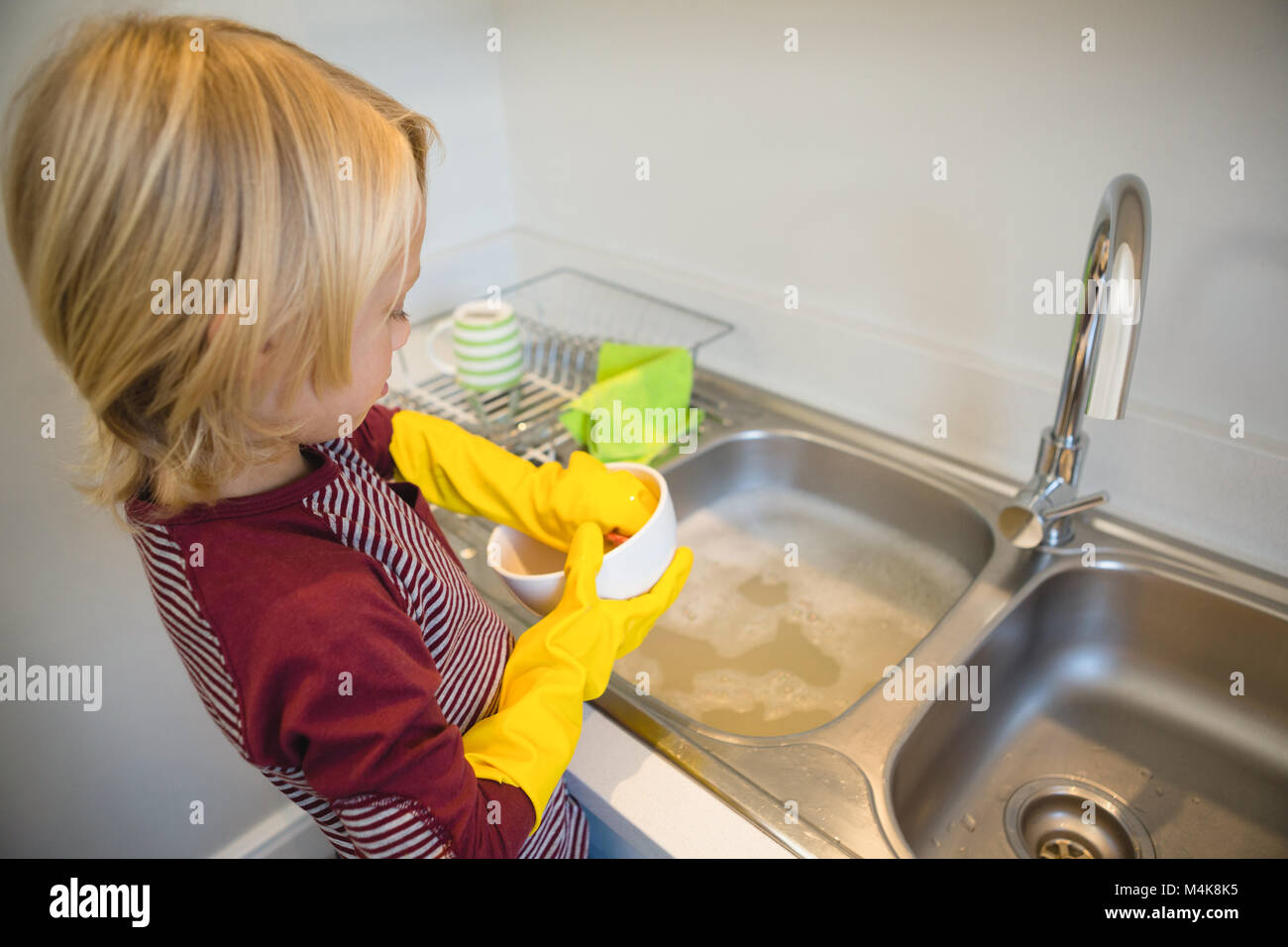 Boy washing utensil in kitchen Stock Photo