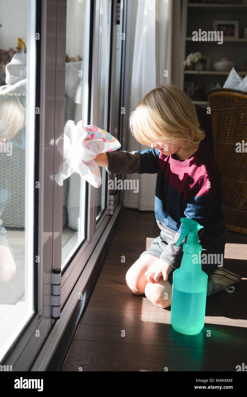 Boy cleaning window with rag cloth Stock Photo