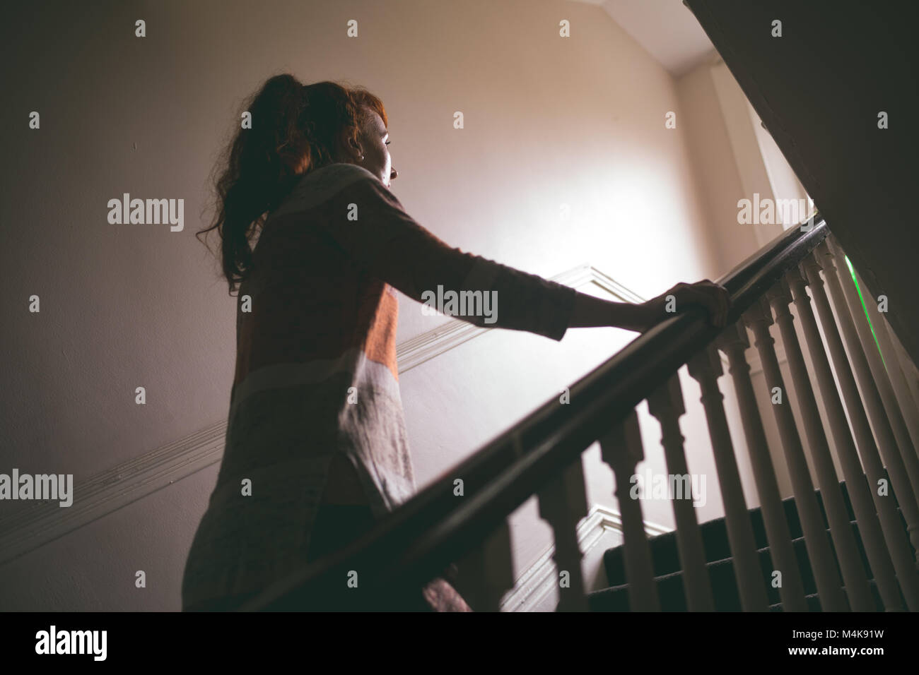 Woman walking upstairs at home Stock Photo