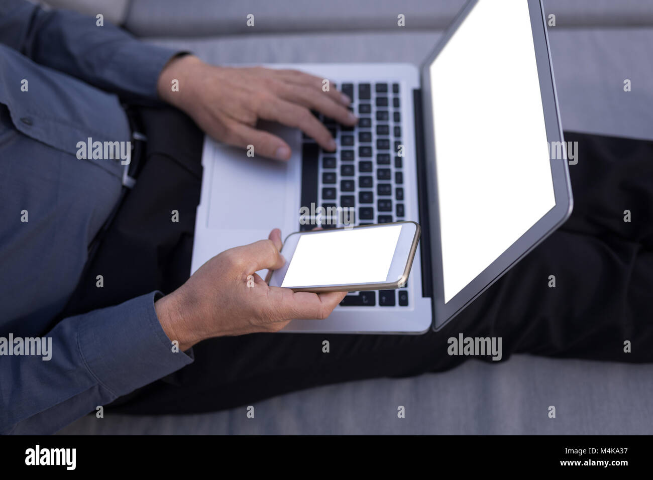 Businessman using mobile phone while working on laptop Stock Photo - Alamy