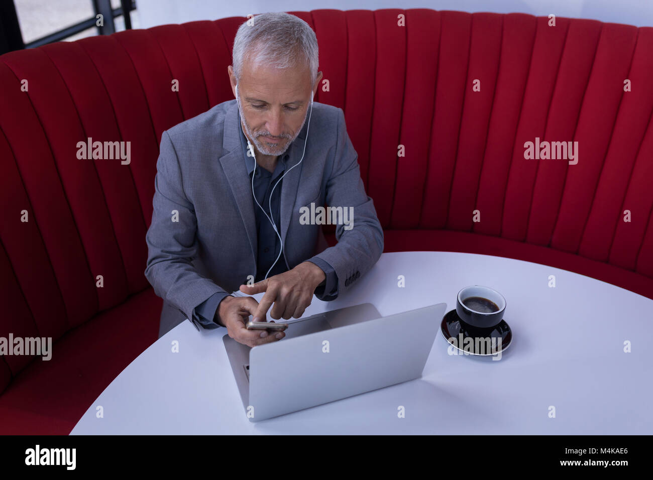 Businessman using mobile phone while working on laptop Stock Photo - Alamy