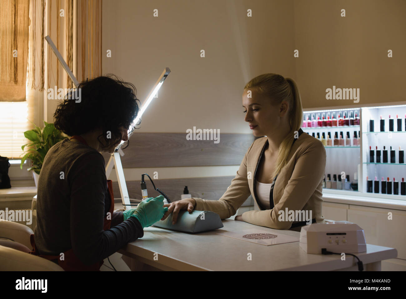 Beautician giving manicure treatment to female customer Stock Photo