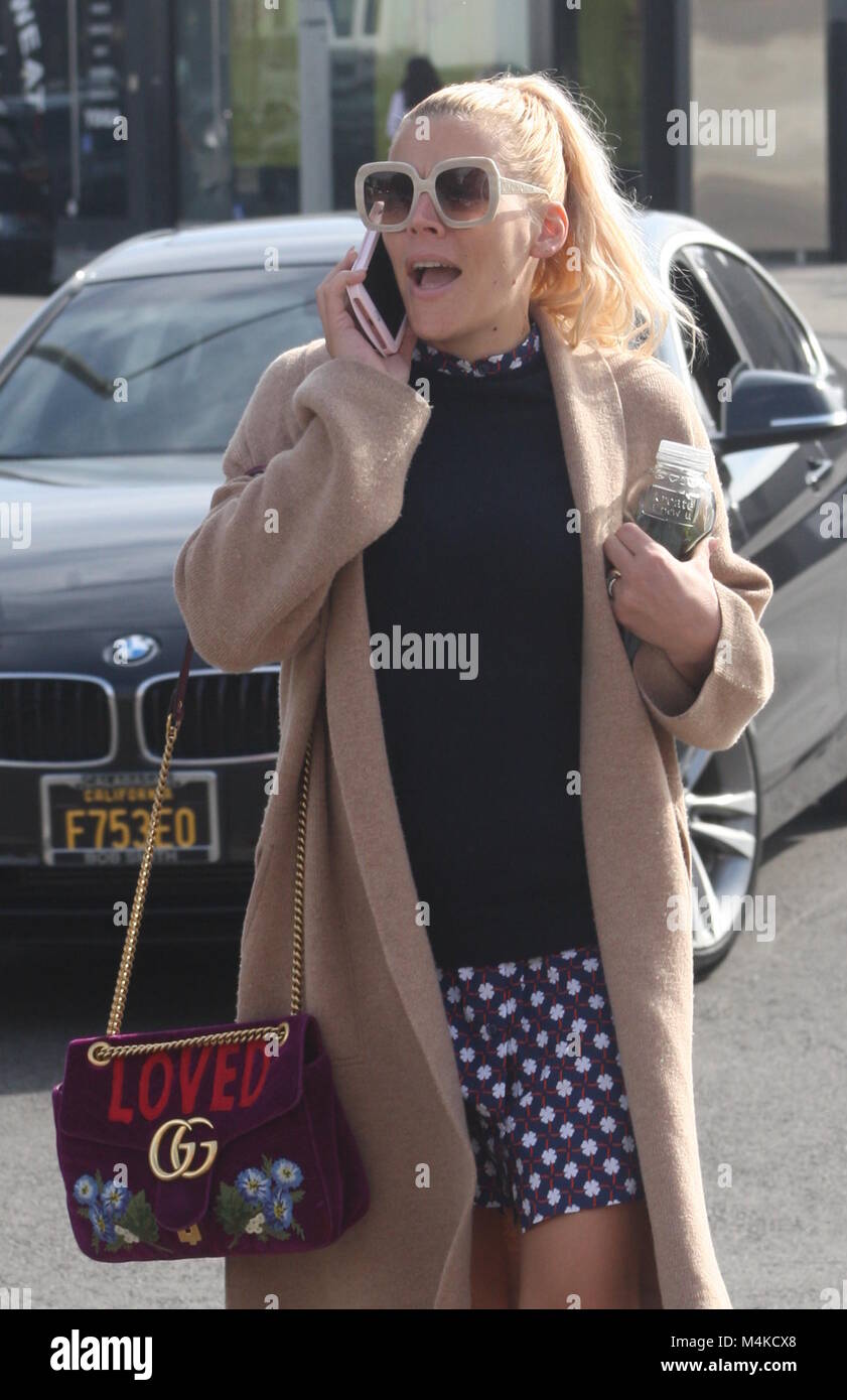 Busy Philipps wears a trench coat and carries a Gucci purse as she has