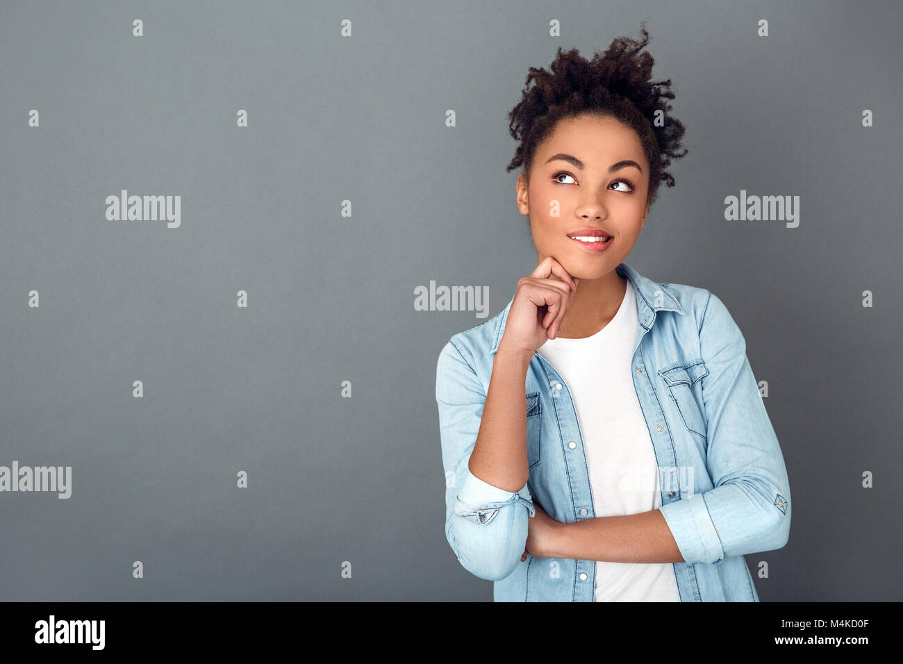 Young african woman isolated on grey wall studio casual daily lifestyle biting lip Stock Photo
