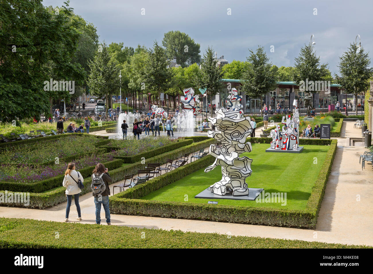 Young tourists taking pictures and having fun at the outdoor display of Jean du Buffet sculptures at the Rijksmuseum in Amsterdam, Netherlands. Stock Photo