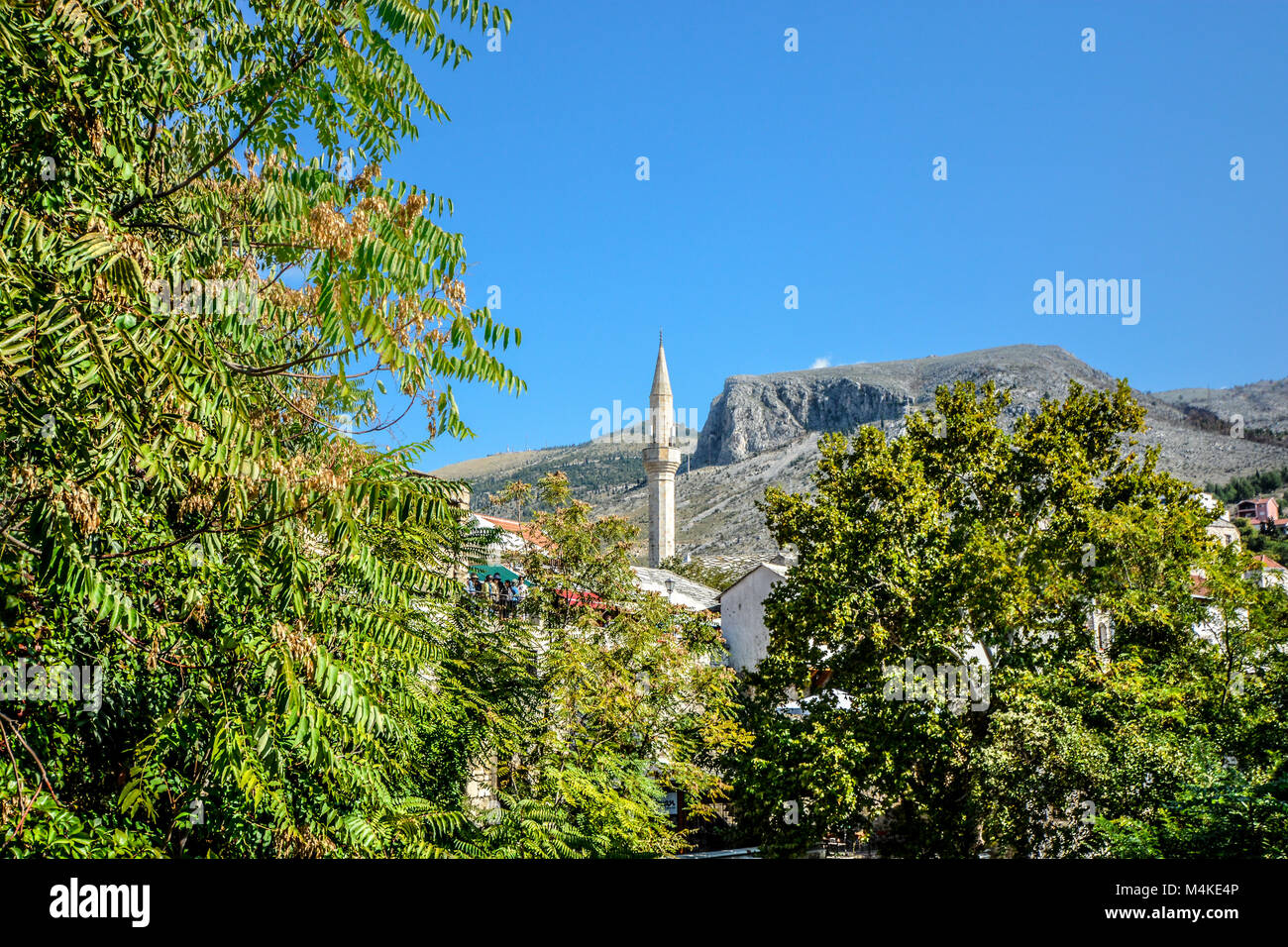 A white minaret towers over old town Mostar Bosnia and Herzegovina near the old bridge on a sunny summer day. Stock Photo